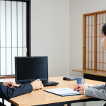 A young professional confidently participating in a Japanese business meeting. The scene should emphasize clear and logical communication, with subtle cues of attentive listening and understanding of non-verbal cues. Focus on a modern, clean office environment.